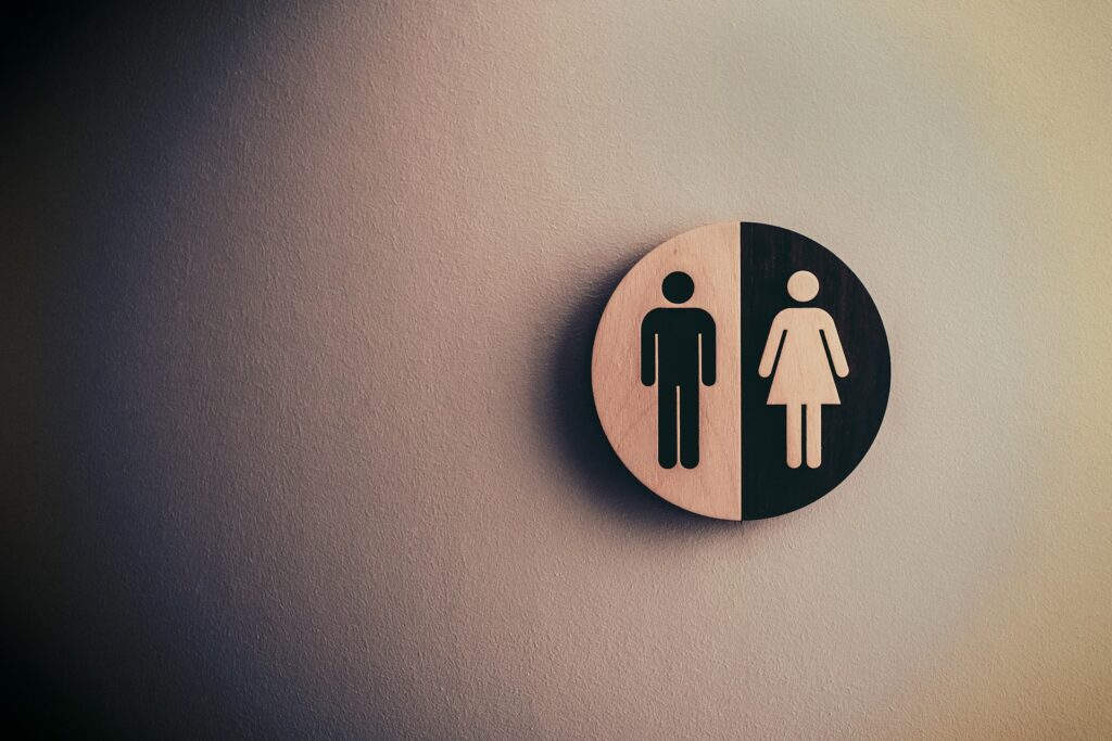 Beiger Hintergrund, links schwarze Schatierung, rechts ein rundes Zeichen von Mann und Frau, einmal Schwarz und einmal Beige.